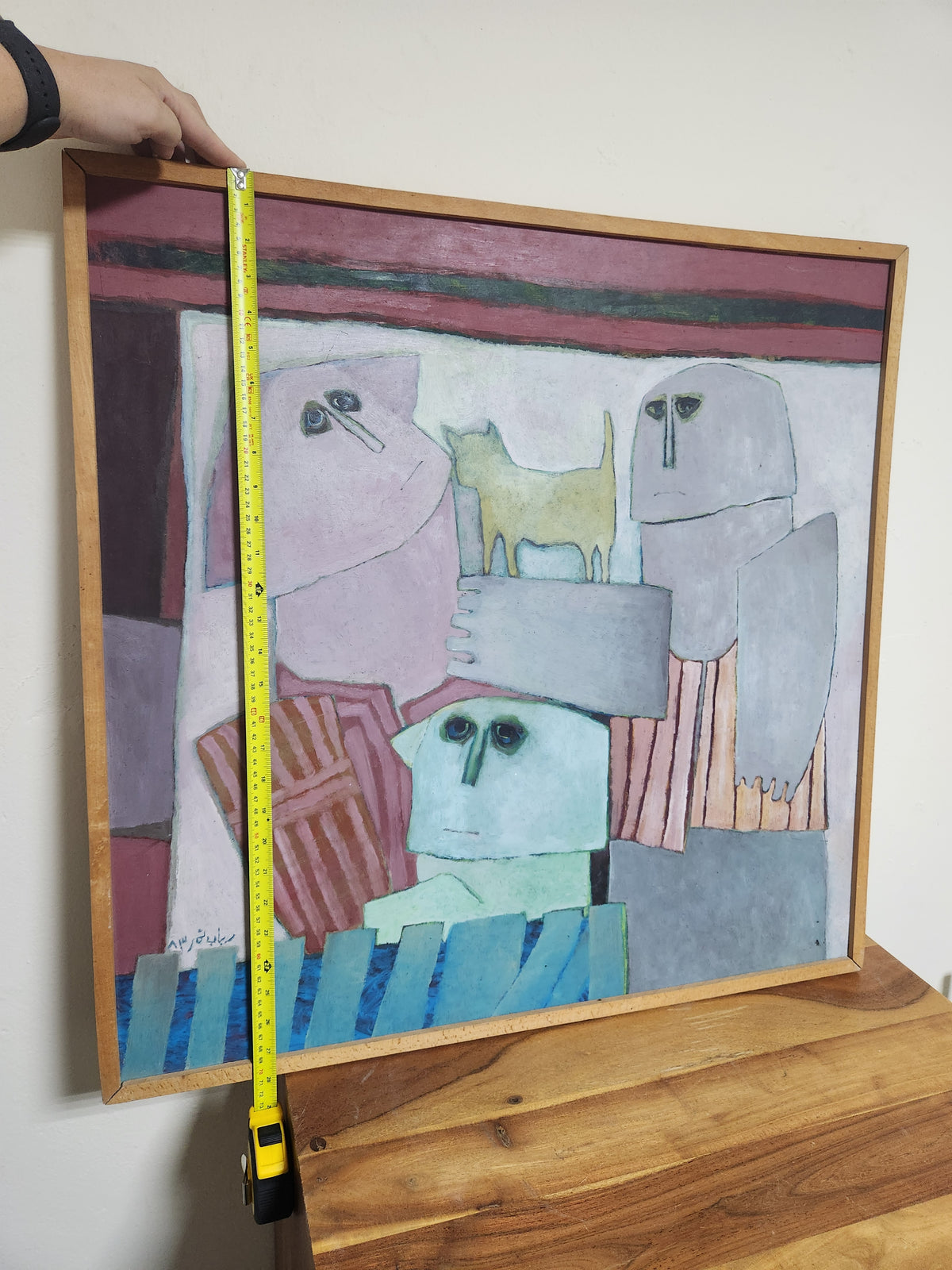 Rabab Nemr painting held against the wall with a tape measure showing the framed height, approx. 72 cm